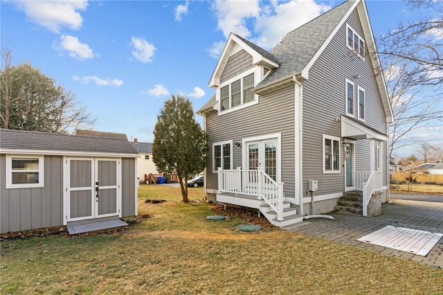 rear view of house featuring a lawn and a storage shed