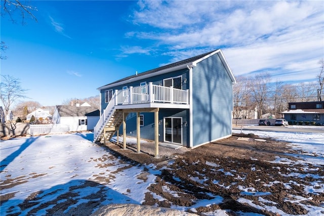 snow covered house featuring a wooden deck