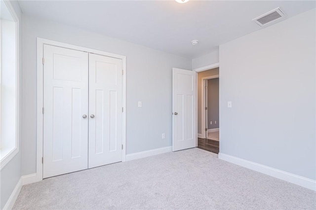 unfurnished bedroom with light carpet and a closet