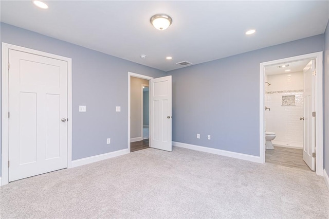 unfurnished bedroom with connected bathroom and light carpet