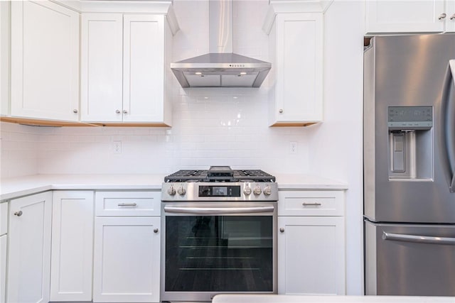 kitchen featuring tasteful backsplash, stainless steel appliances, wall chimney range hood, and white cabinets