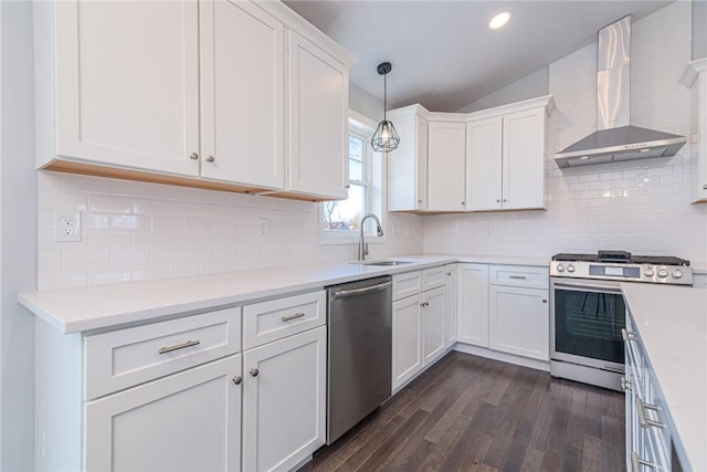 kitchen with stainless steel appliances, white cabinetry, sink, and wall chimney range hood