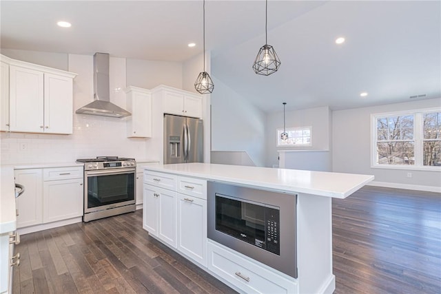 kitchen featuring white cabinetry, vaulted ceiling, wall chimney exhaust hood, and appliances with stainless steel finishes