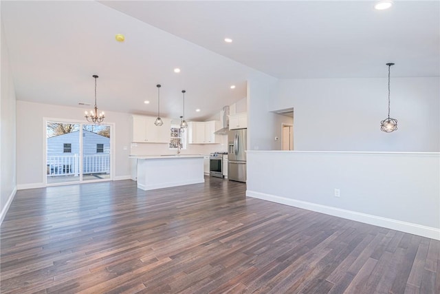 unfurnished living room with lofted ceiling, dark wood-type flooring, sink, and a notable chandelier