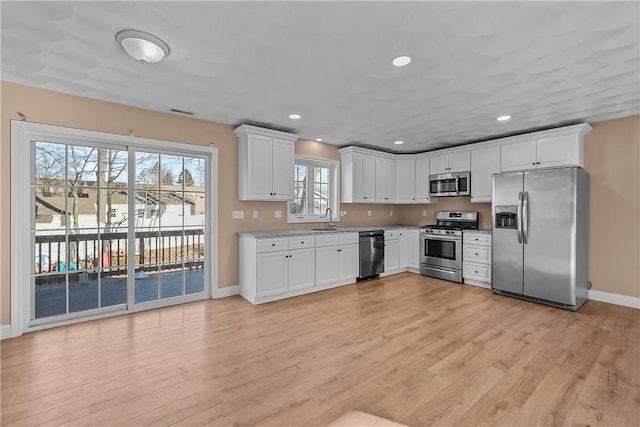 kitchen featuring sink, light hardwood / wood-style flooring, white cabinets, and appliances with stainless steel finishes