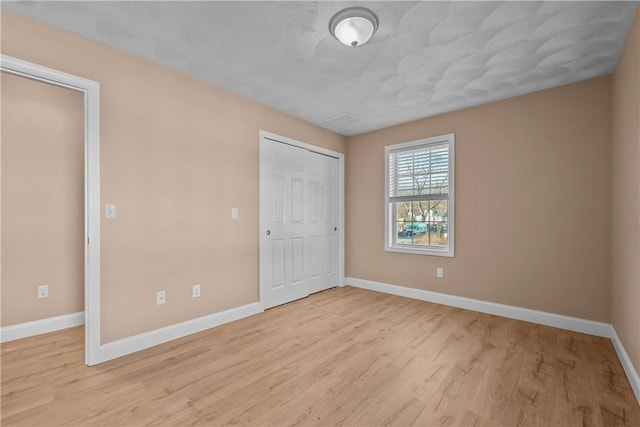 unfurnished bedroom with light hardwood / wood-style flooring and a closet