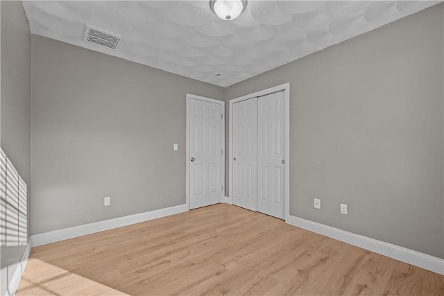 unfurnished bedroom featuring light hardwood / wood-style floors and a closet