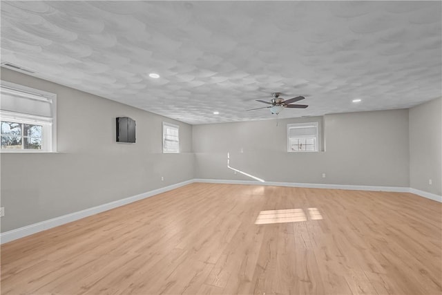 basement featuring ceiling fan, light hardwood / wood-style floors, and a wealth of natural light