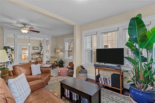 living room featuring a baseboard radiator, ceiling fan, and ornate columns