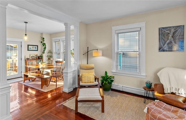 living area with decorative columns, hardwood / wood-style floors, and baseboard heating