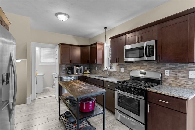 kitchen with pendant lighting, light stone counters, stainless steel appliances, and decorative backsplash