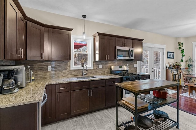 kitchen featuring sink, stainless steel appliances, light stone countertops, decorative backsplash, and decorative light fixtures