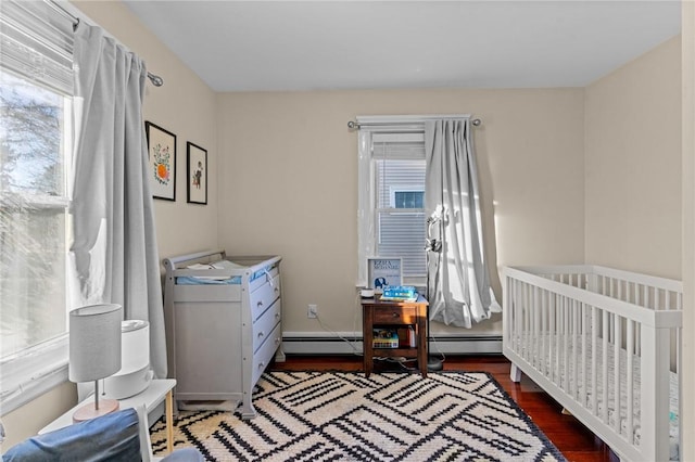 bedroom featuring dark wood-type flooring, a nursery area, and a baseboard radiator