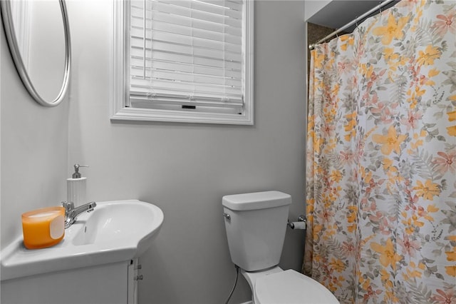 bathroom featuring walk in shower, toilet, and sink