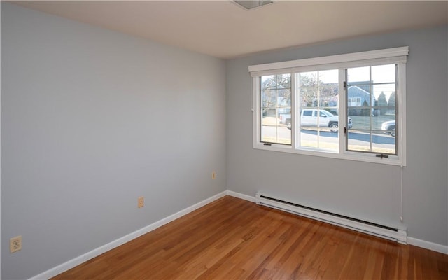 empty room with hardwood / wood-style flooring and a baseboard heating unit