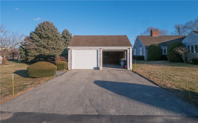 view of front of house featuring a garage, an outdoor structure, and a front lawn