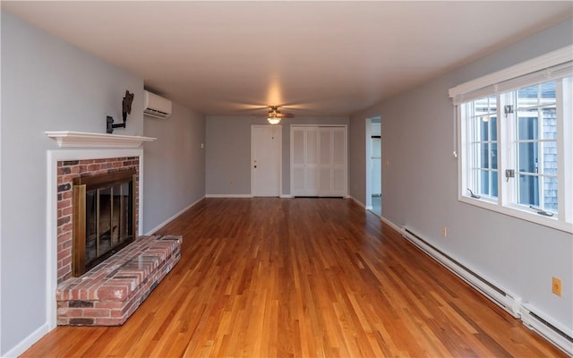 unfurnished living room with a brick fireplace, a baseboard radiator, hardwood / wood-style floors, and a wall mounted AC