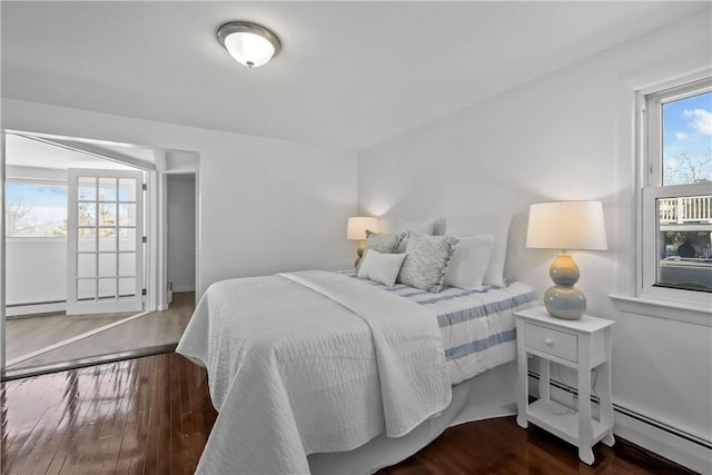 bedroom featuring multiple windows, a baseboard heating unit, and dark hardwood / wood-style flooring