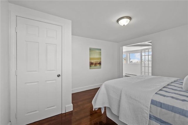 bedroom featuring a baseboard heating unit and dark wood-type flooring