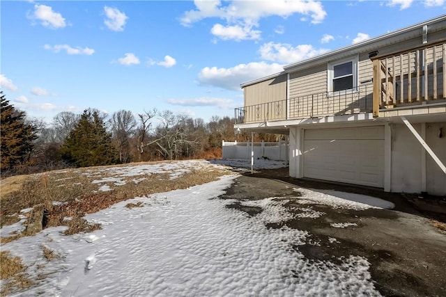 snow covered property featuring a garage and a balcony