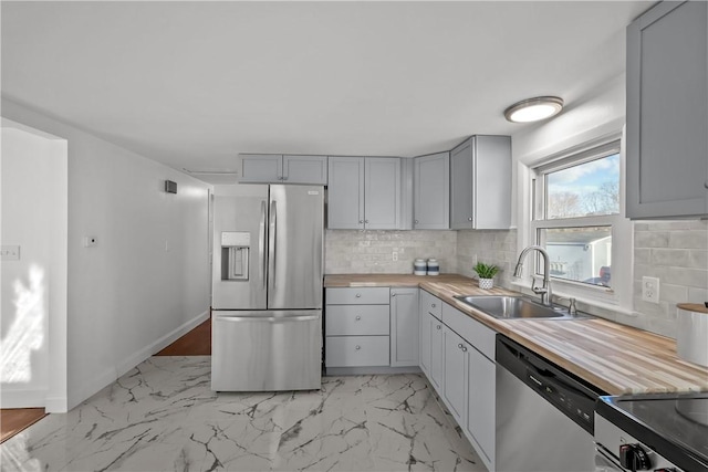 kitchen featuring sink, wooden counters, appliances with stainless steel finishes, gray cabinetry, and backsplash