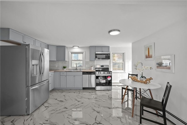 kitchen with tasteful backsplash, stainless steel appliances, sink, and gray cabinetry