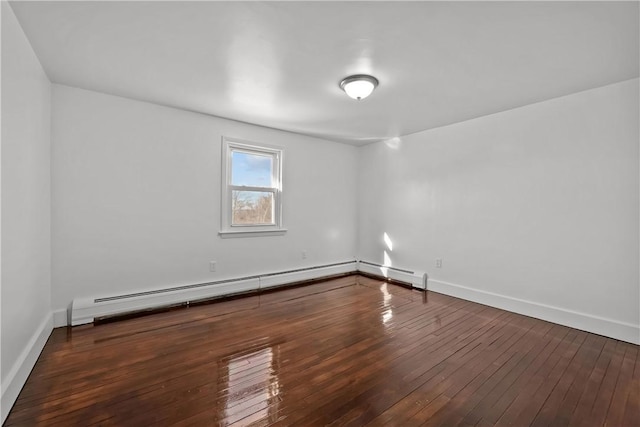 spare room with dark wood-type flooring and a baseboard heating unit