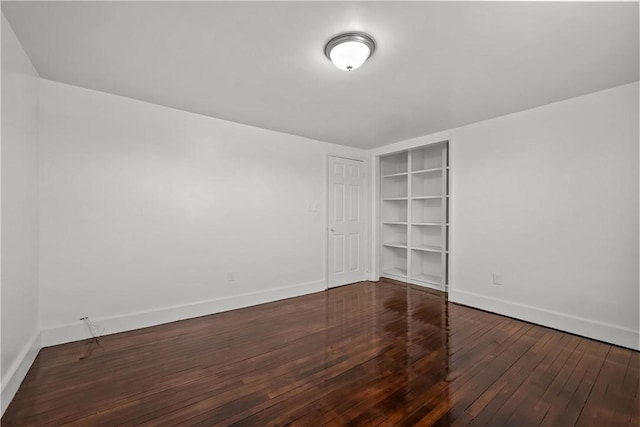 spare room featuring dark wood-type flooring and built in features