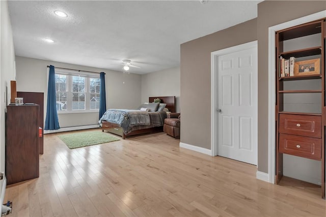 bedroom with light hardwood / wood-style flooring, ceiling fan, and baseboard heating