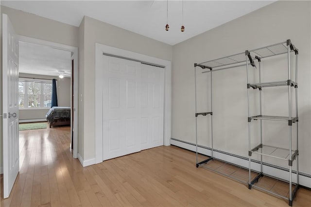 interior space with hardwood / wood-style flooring, a closet, and a baseboard heating unit