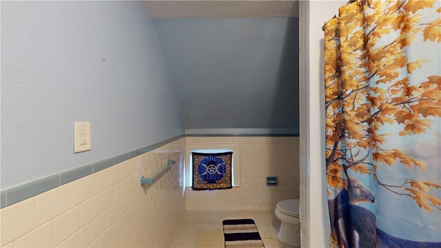 bathroom featuring tile patterned flooring, tile walls, and toilet