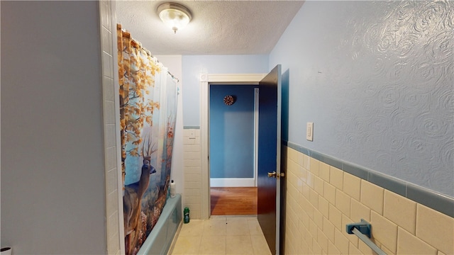 corridor featuring tile walls and a textured ceiling