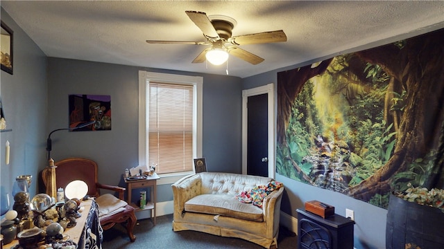 living area featuring ceiling fan, carpet floors, and a textured ceiling