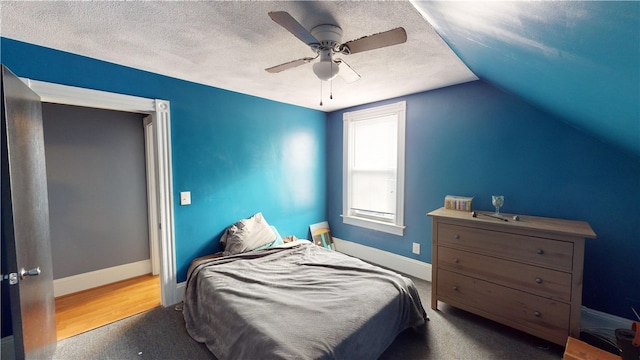 bedroom featuring ceiling fan, carpet floors, vaulted ceiling, and a textured ceiling