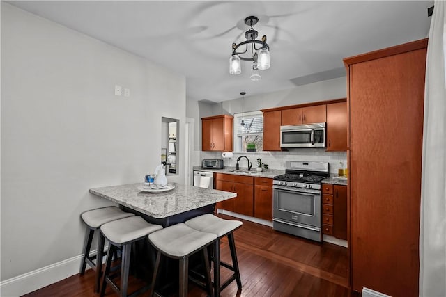 kitchen featuring hanging light fixtures, appliances with stainless steel finishes, a kitchen breakfast bar, kitchen peninsula, and backsplash