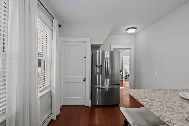 kitchen with light stone counters, dark wood-type flooring, stainless steel fridge, and a healthy amount of sunlight