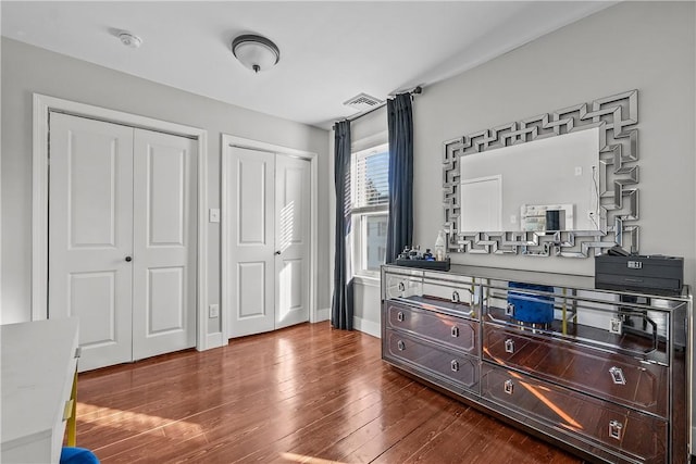 bedroom with dark wood-type flooring and multiple closets