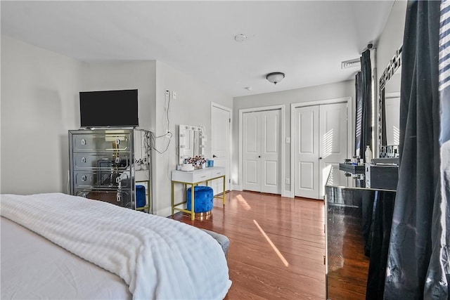 bedroom featuring hardwood / wood-style floors and two closets