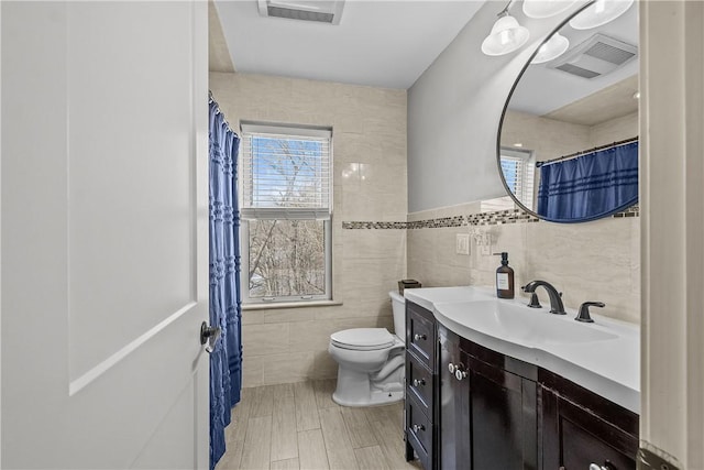 bathroom featuring vanity, toilet, and tile walls