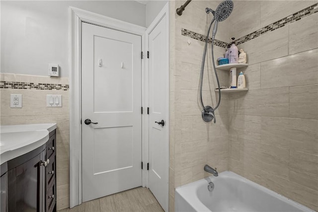 bathroom featuring vanity, tiled shower / bath combo, and tile walls