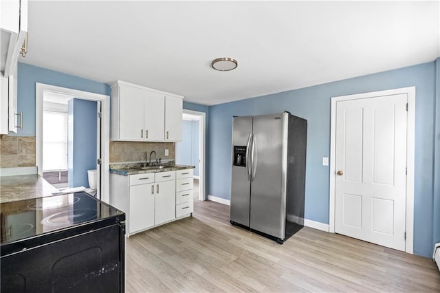 kitchen with white cabinetry, stainless steel refrigerator with ice dispenser, sink, and electric range