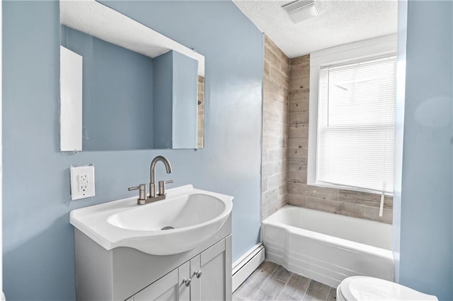 bathroom with baseboard heating, vanity, a textured ceiling, a tub, and toilet