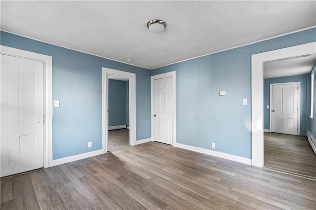 unfurnished bedroom with a baseboard radiator, light hardwood / wood-style flooring, and a textured ceiling