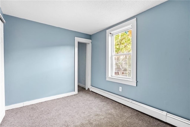 carpeted empty room featuring a baseboard heating unit