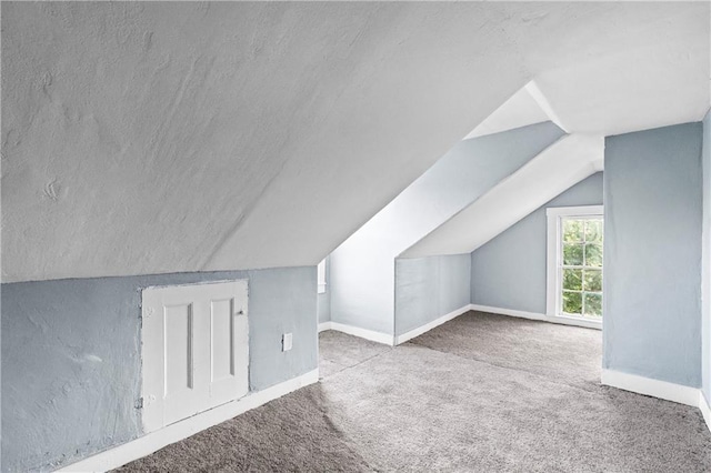 bonus room with lofted ceiling, light carpet, and a textured ceiling