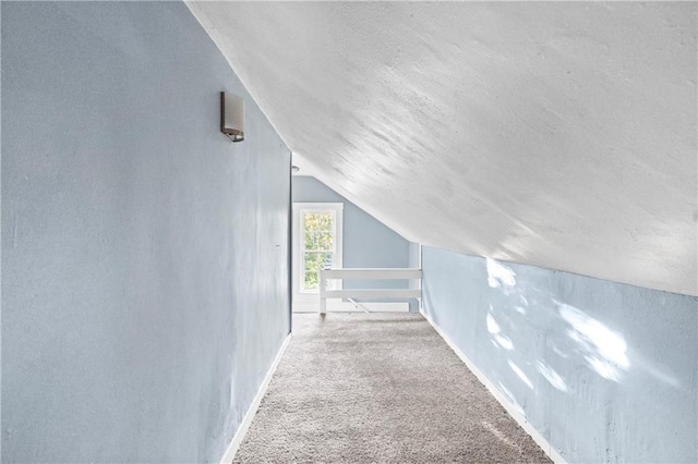 additional living space featuring vaulted ceiling, light carpet, and a textured ceiling