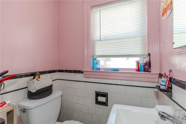 bathroom with toilet, sink, and tile walls