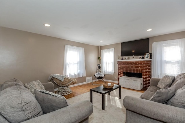 living room featuring light hardwood / wood-style floors and a brick fireplace