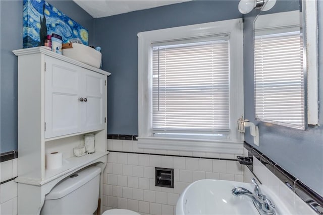 bathroom featuring sink, tile walls, and toilet