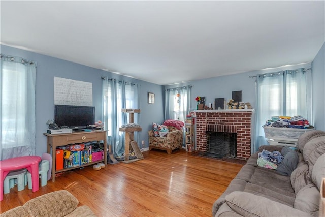 living room featuring wood-type flooring, a fireplace, and plenty of natural light